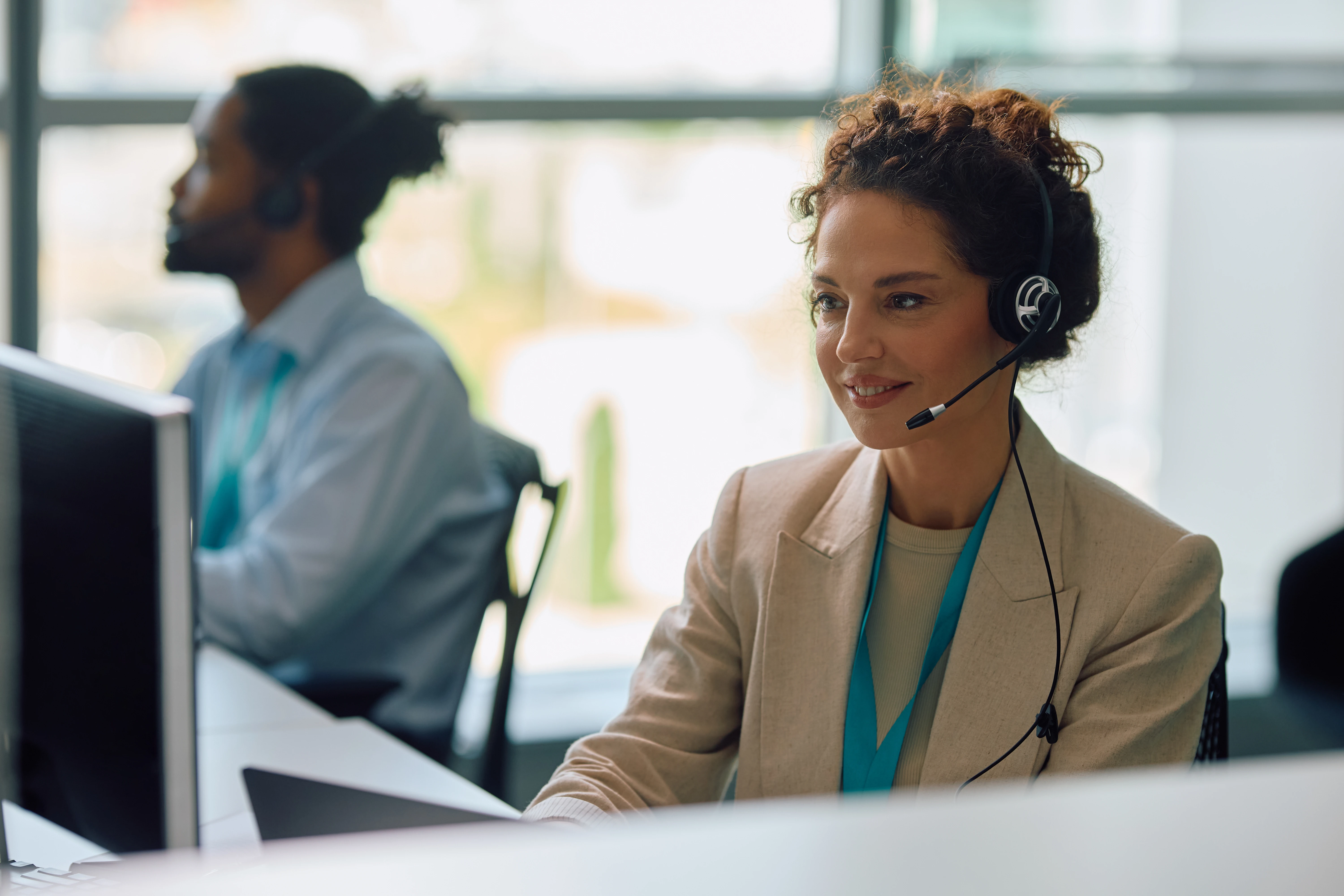 A woman looking at the computer wearing a headset