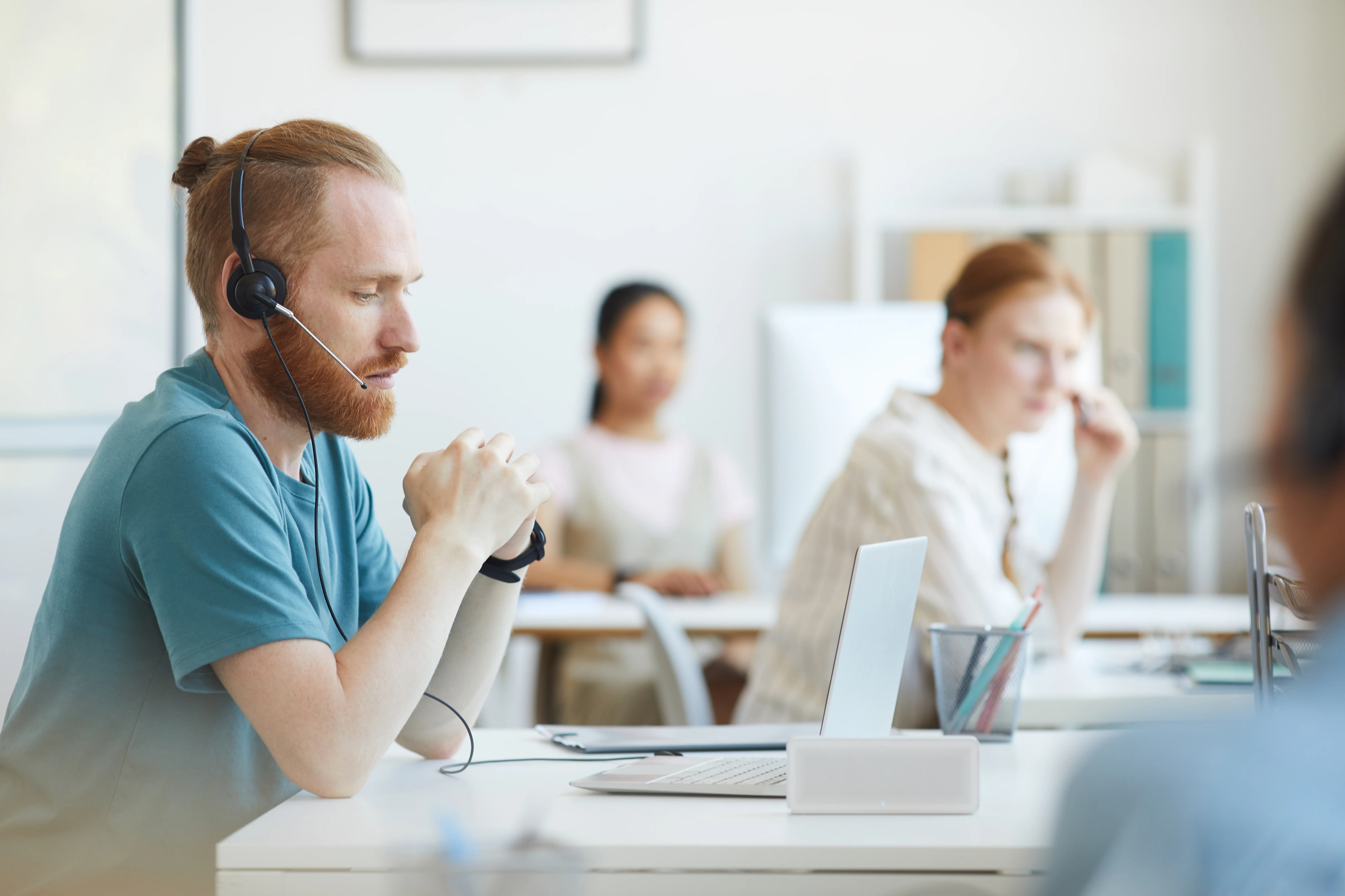 A man waiting on a call. He's wearing a headset, staring into the laptop screen.