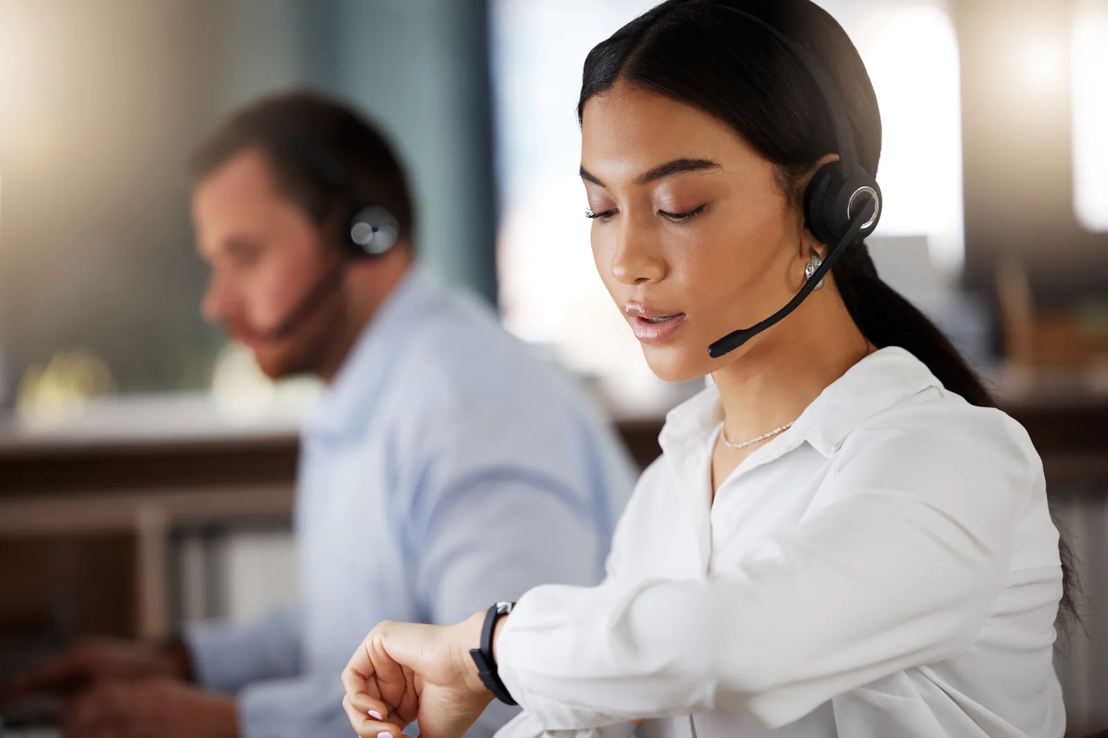 A call agent looking at her watch while she's on the phone.