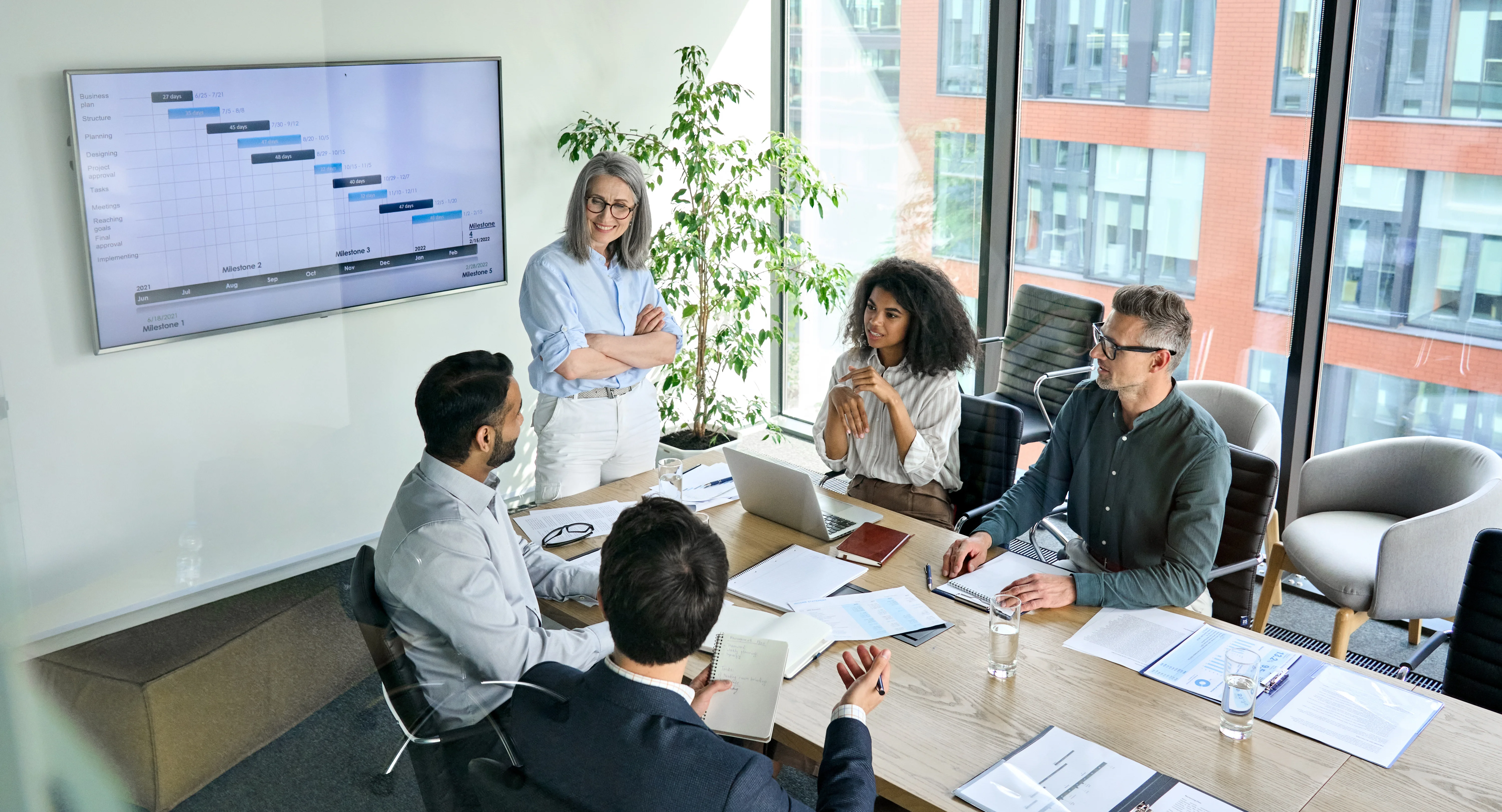 A business meeting with a group of people sat at a conference room table.