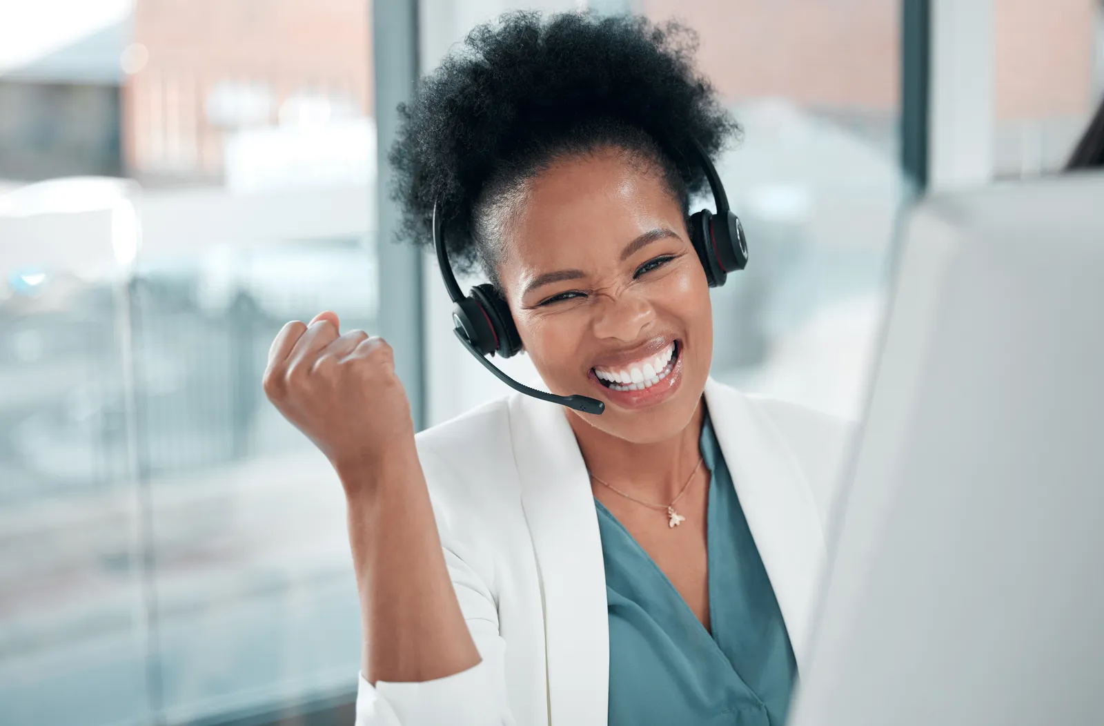 A woman wearing a headset with her fist pumped in the air.