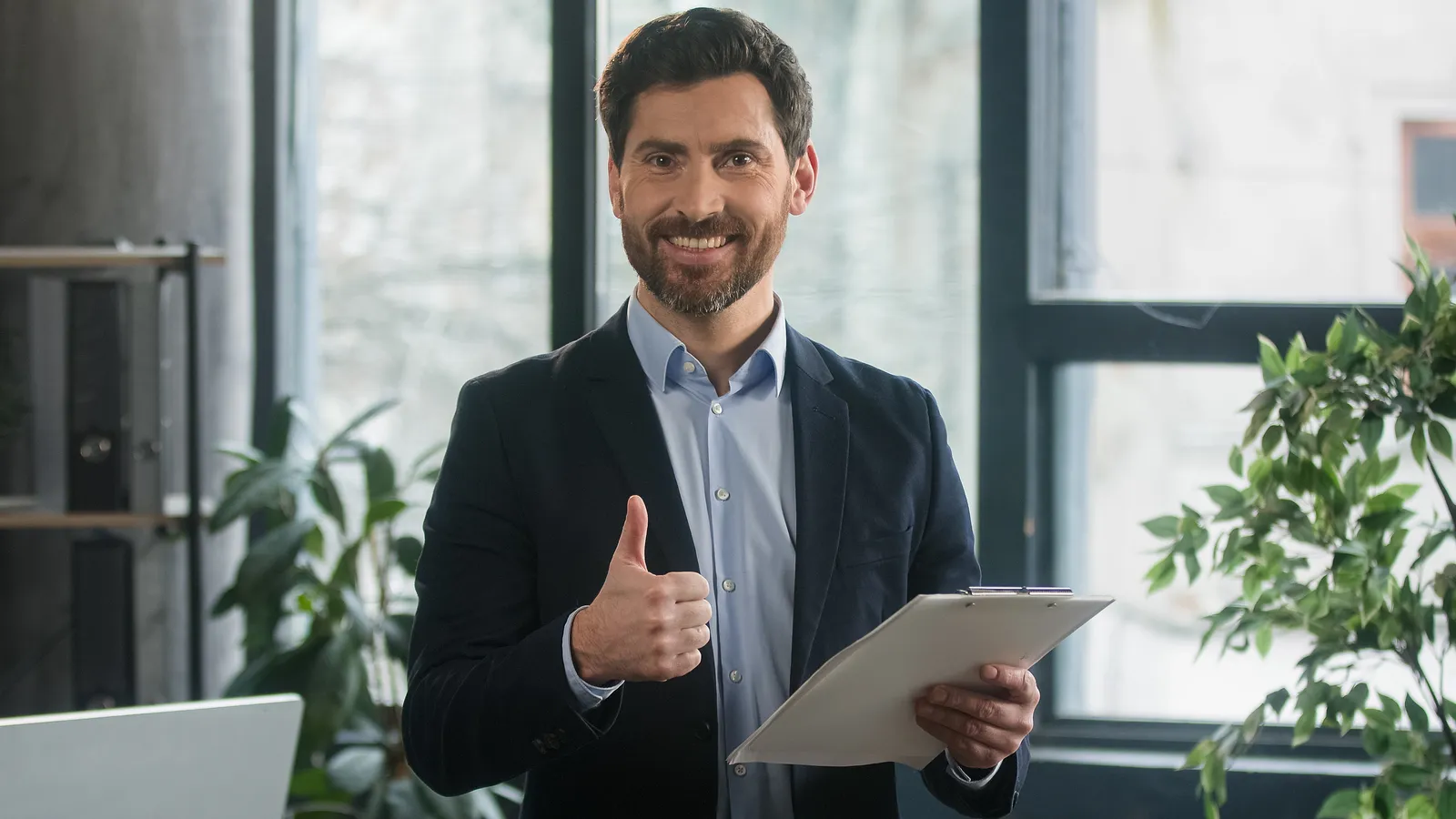 A man holding a clipboard and giving a thumbs up.