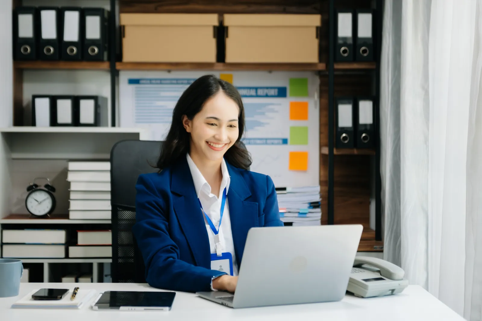 A woman working at her computer and smiling.