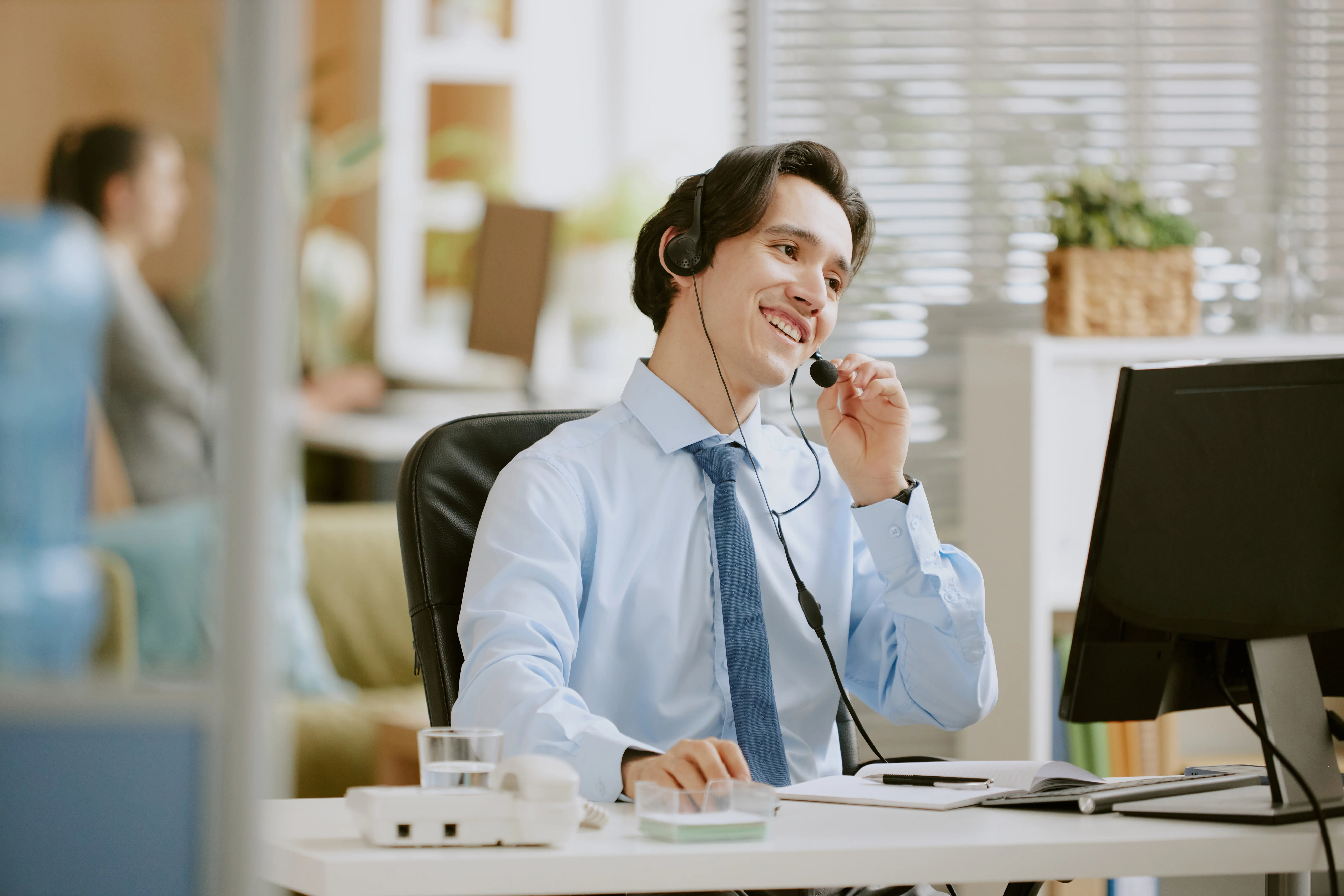 A man wearing a headset and looking at a computer.