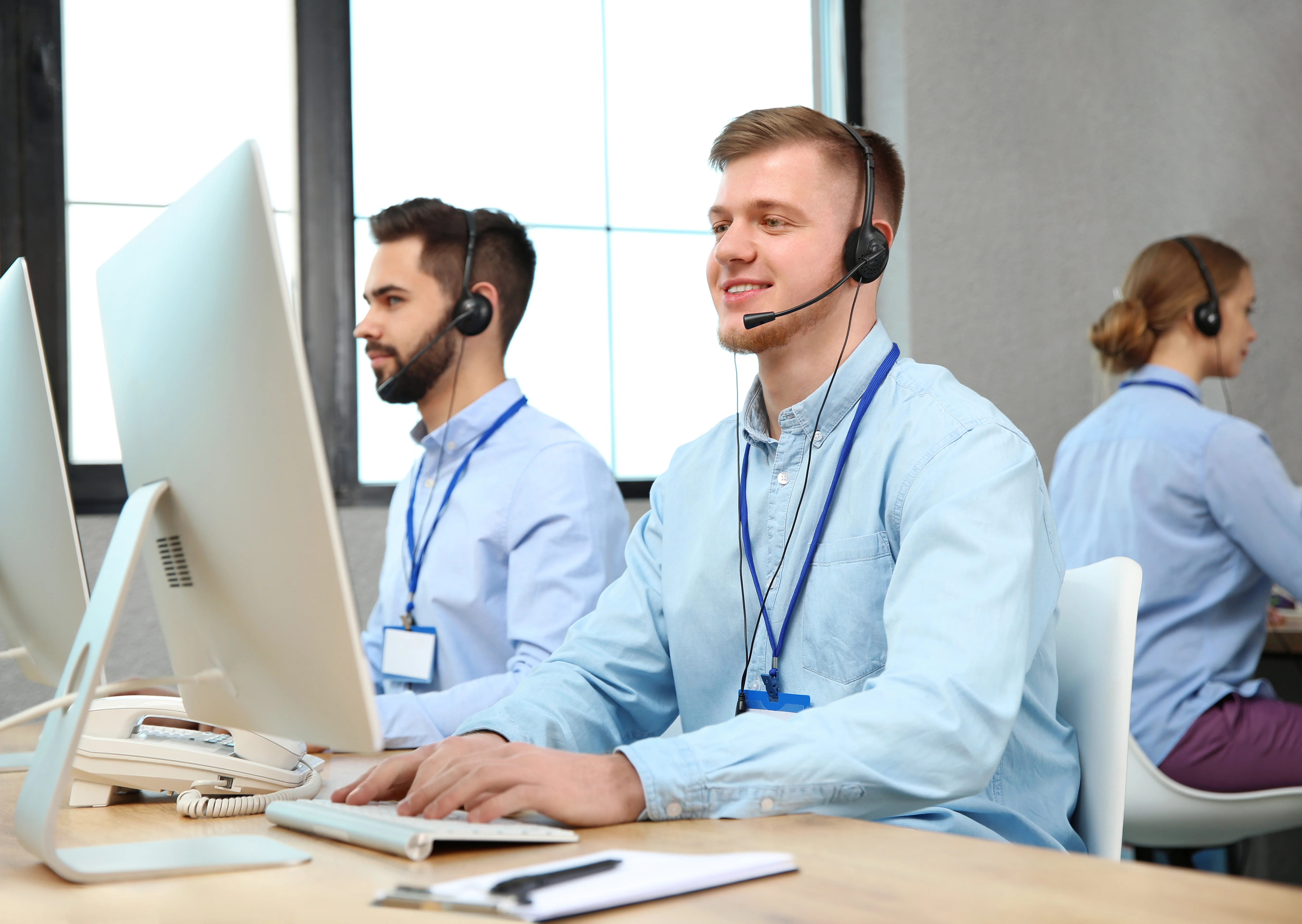 A group of coworkers in an office together. They are all wearing headsets and staring at their computer screens.