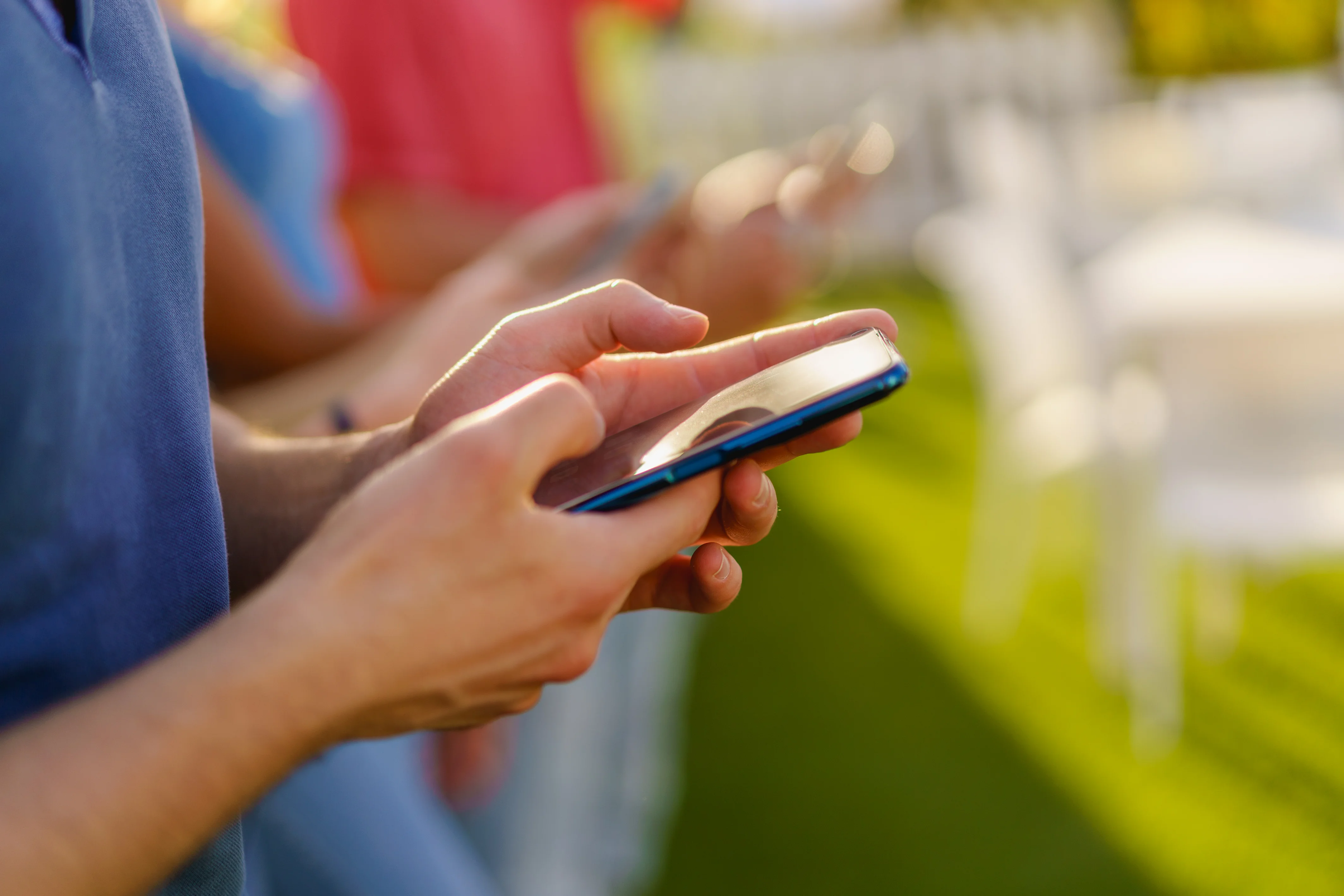 Three friends using their phones outside.