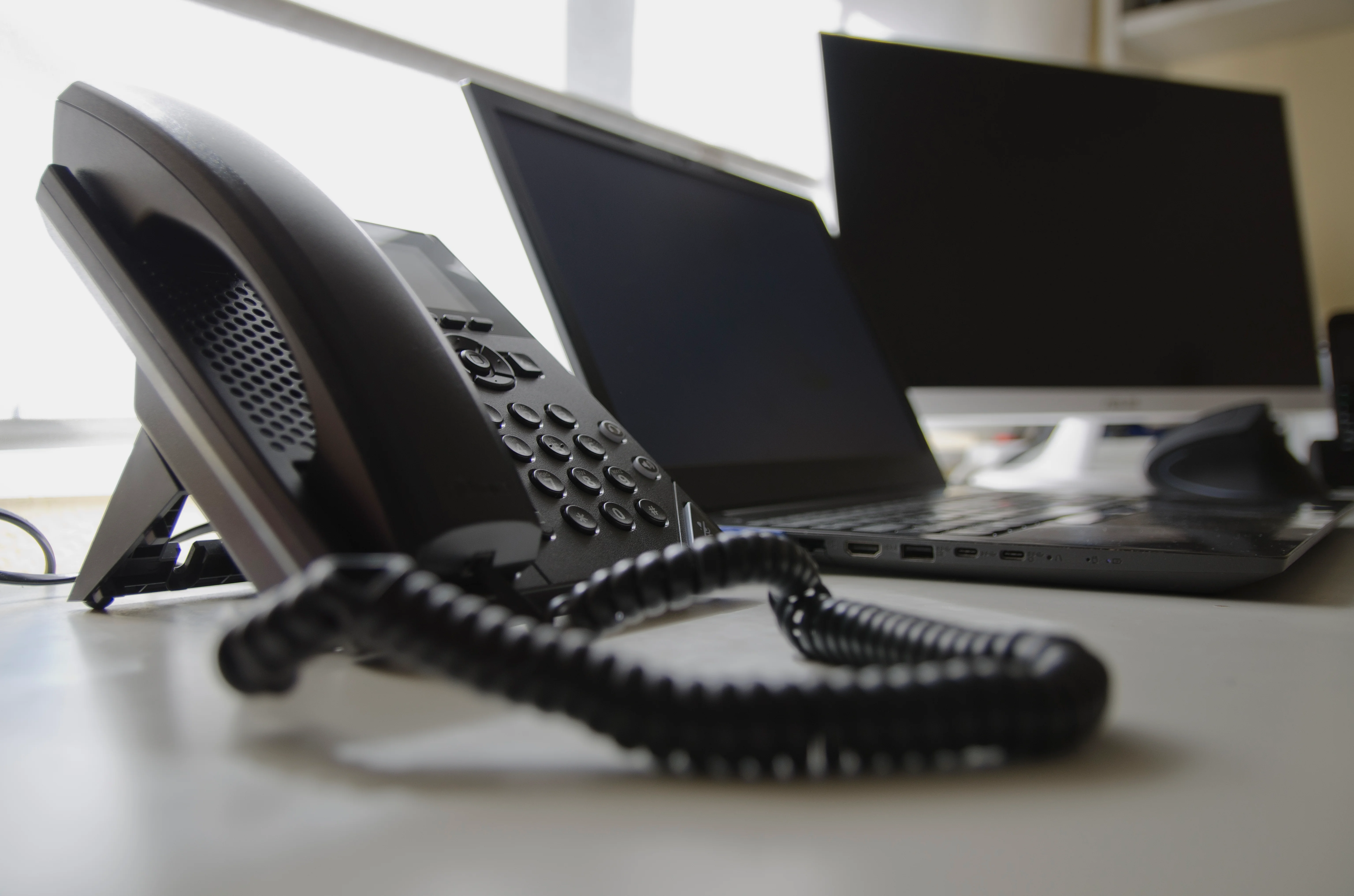 A landline next to a laptop and a monitor.