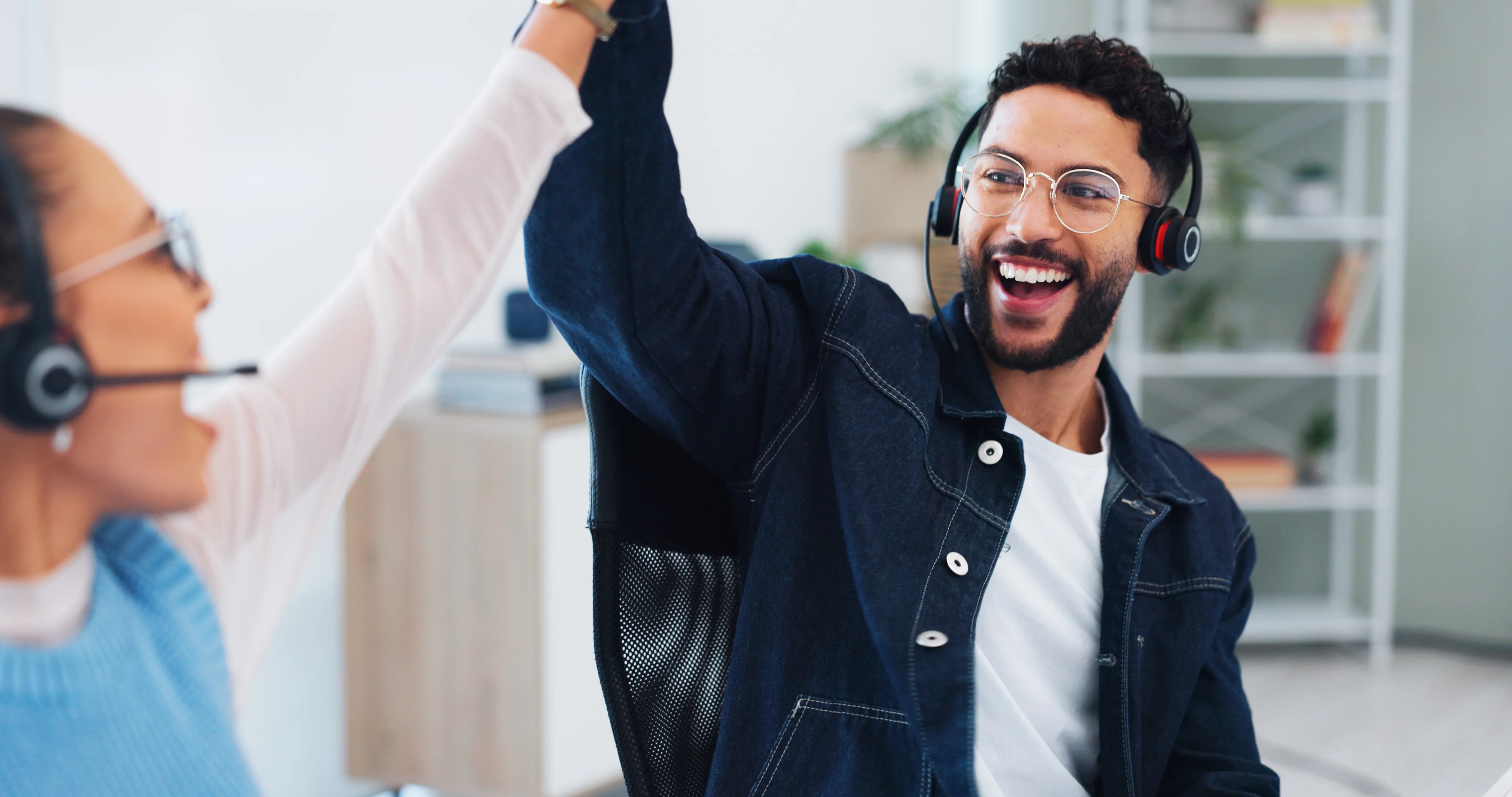 Two people high-fiving each other. They are both wearing headsets and seem to be celebrating.