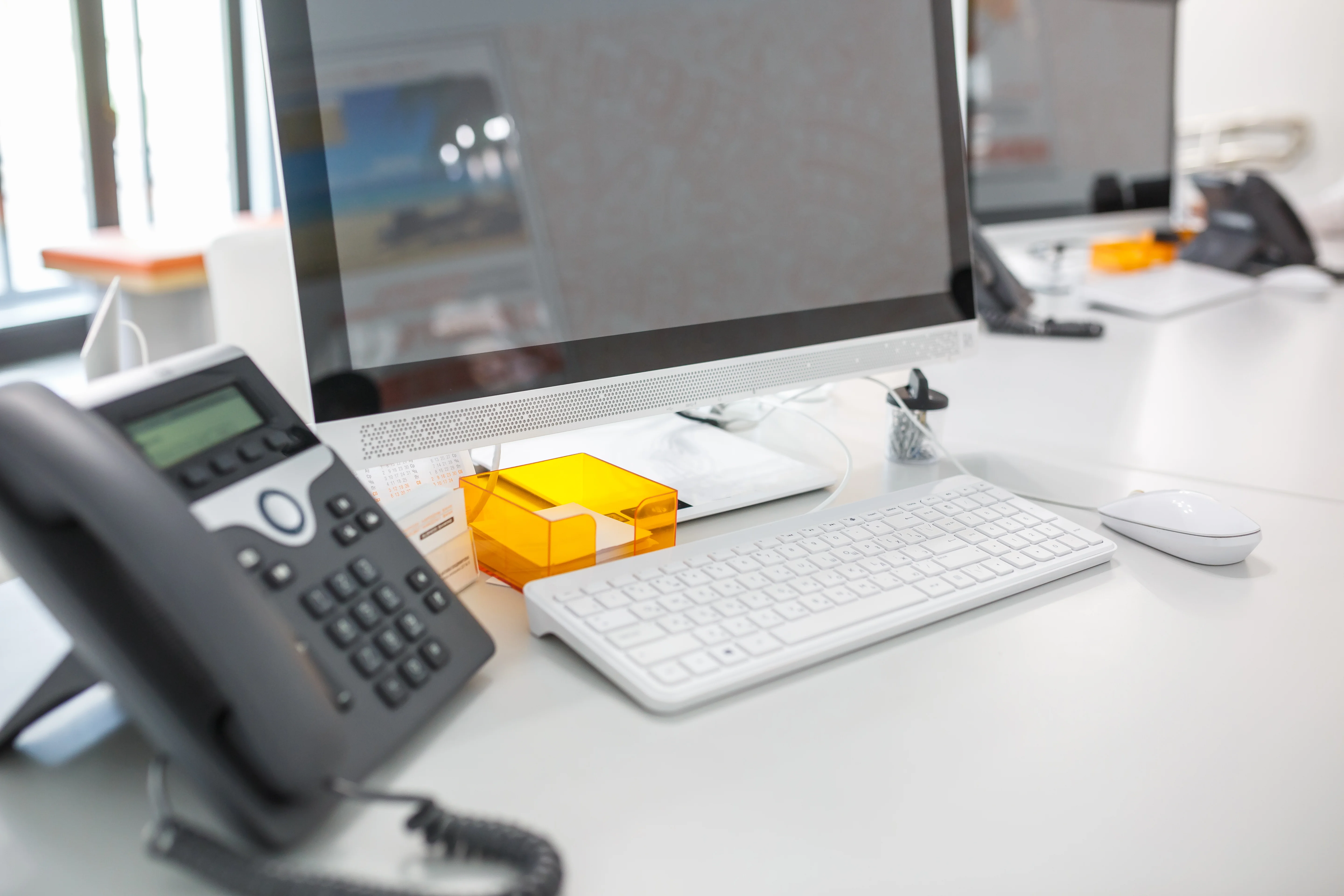 A computer sat next to a phone. It's a neat, organized desk.
